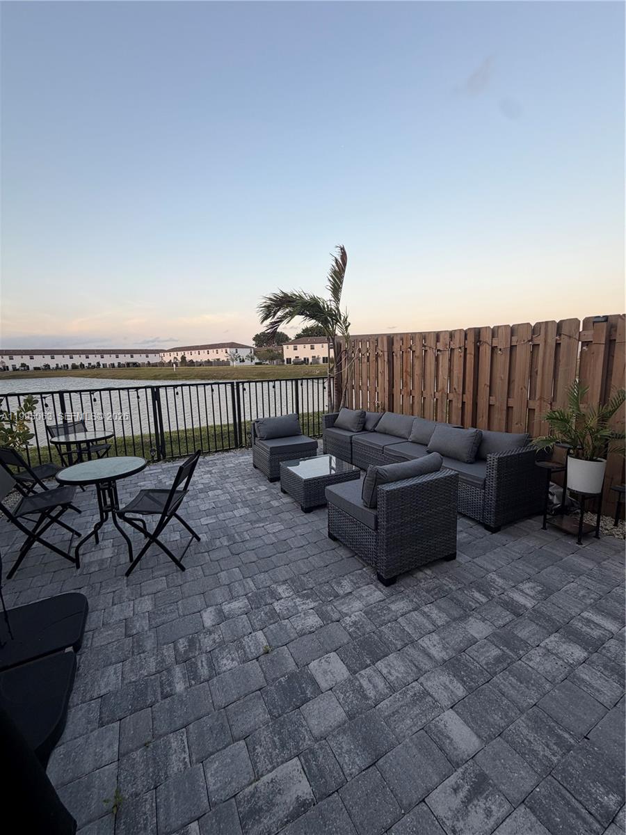 A paved patio features outdoor furniture, a sectional sofa, and a metal fence overlooking water — 2371 NW 122nd Ter, Miami FL 33167, MIAMI, FL