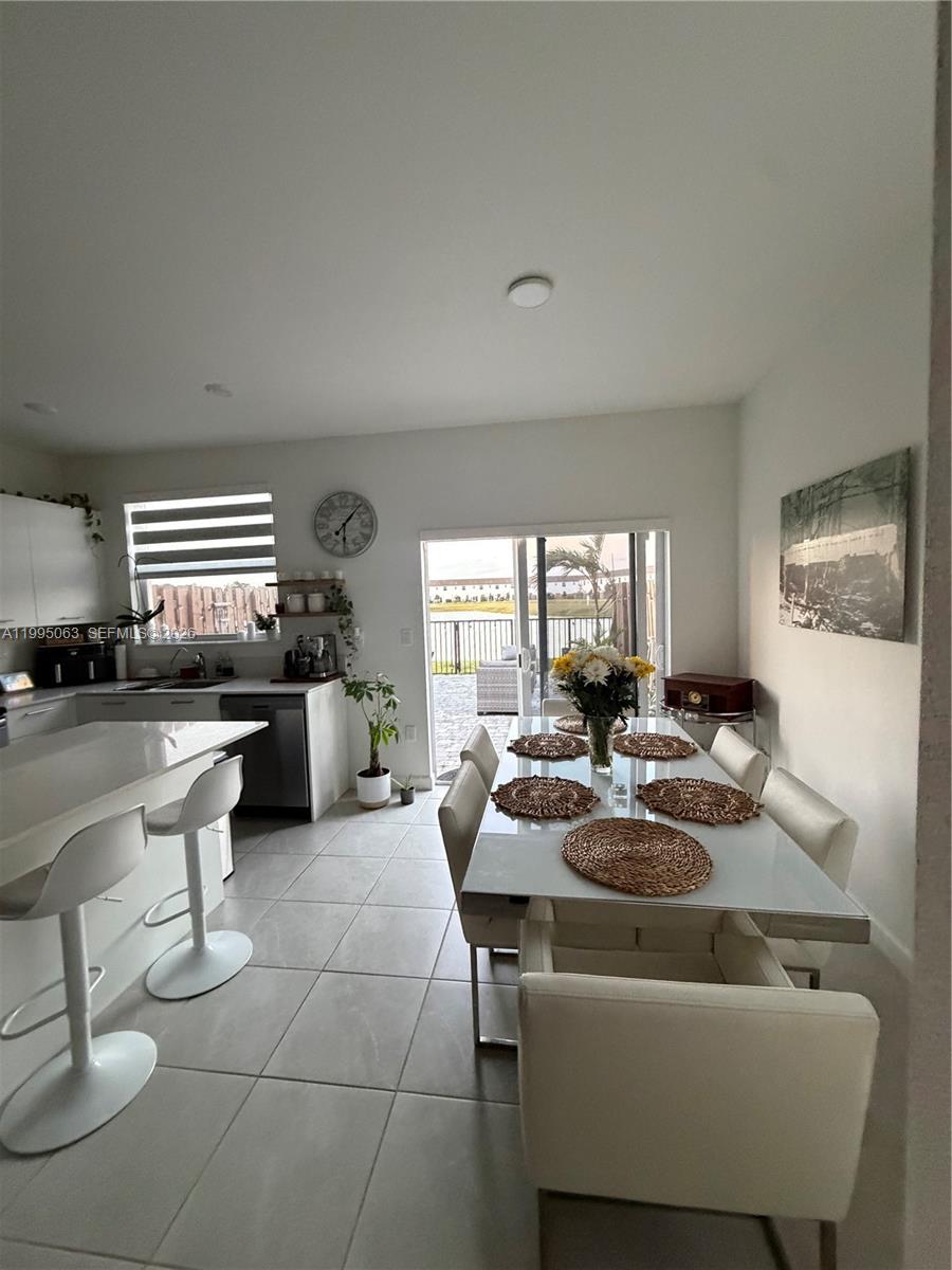 A modern kitchen and dining area with white cabinets, tile floors, and a patio view — 2371 NW 122nd Ter, Miami FL 33167, MIAMI, FL