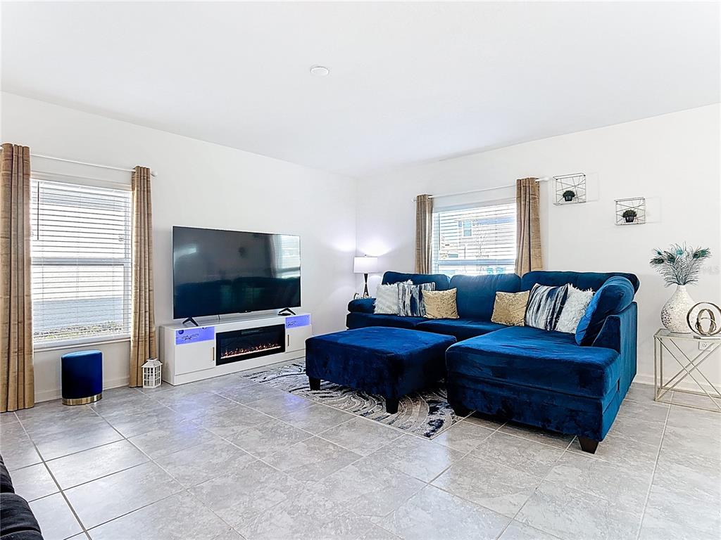 A living room features a blue sectional sofa, a television, and a fireplace console — 629 SAND PINE LANE, HAINES CITY, FL