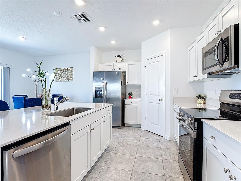 A modern kitchen features white cabinetry, stainless steel appliances, and a large center island — 629 SAND PINE LANE, HAINES CITY, FL