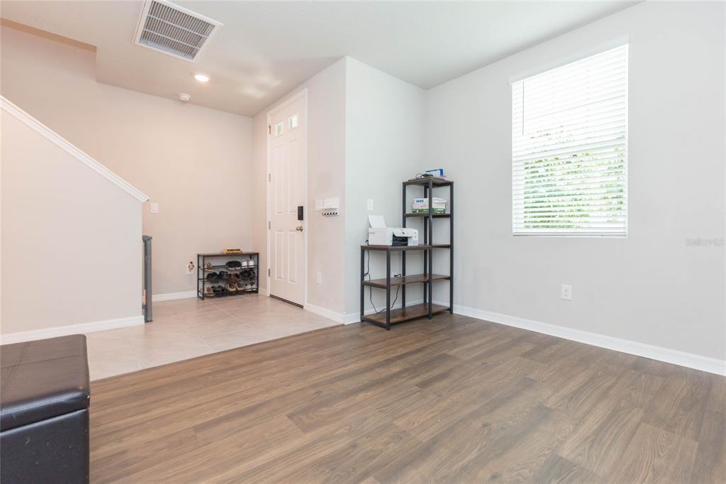 An entryway with tile flooring, a staircase, and a wood-floored room with a shelving unit — 38794 OPAL WILLOW LANE, ZEPHYRHILLS, FL