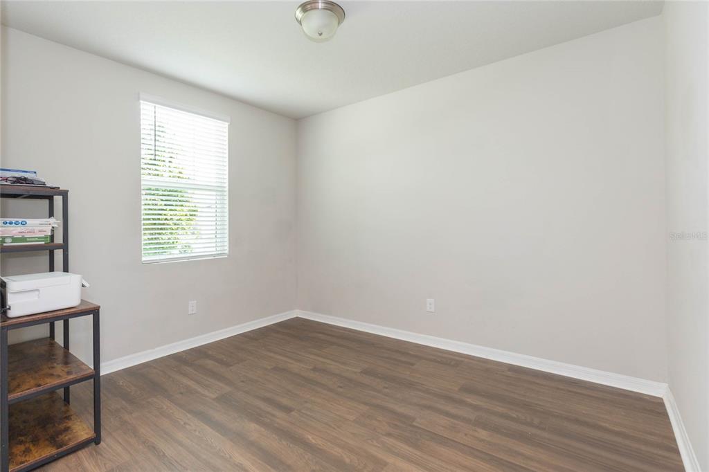 An empty room with light gray walls, wood-look flooring, and a window with blinds — 38794 OPAL WILLOW LANE, ZEPHYRHILLS, FL