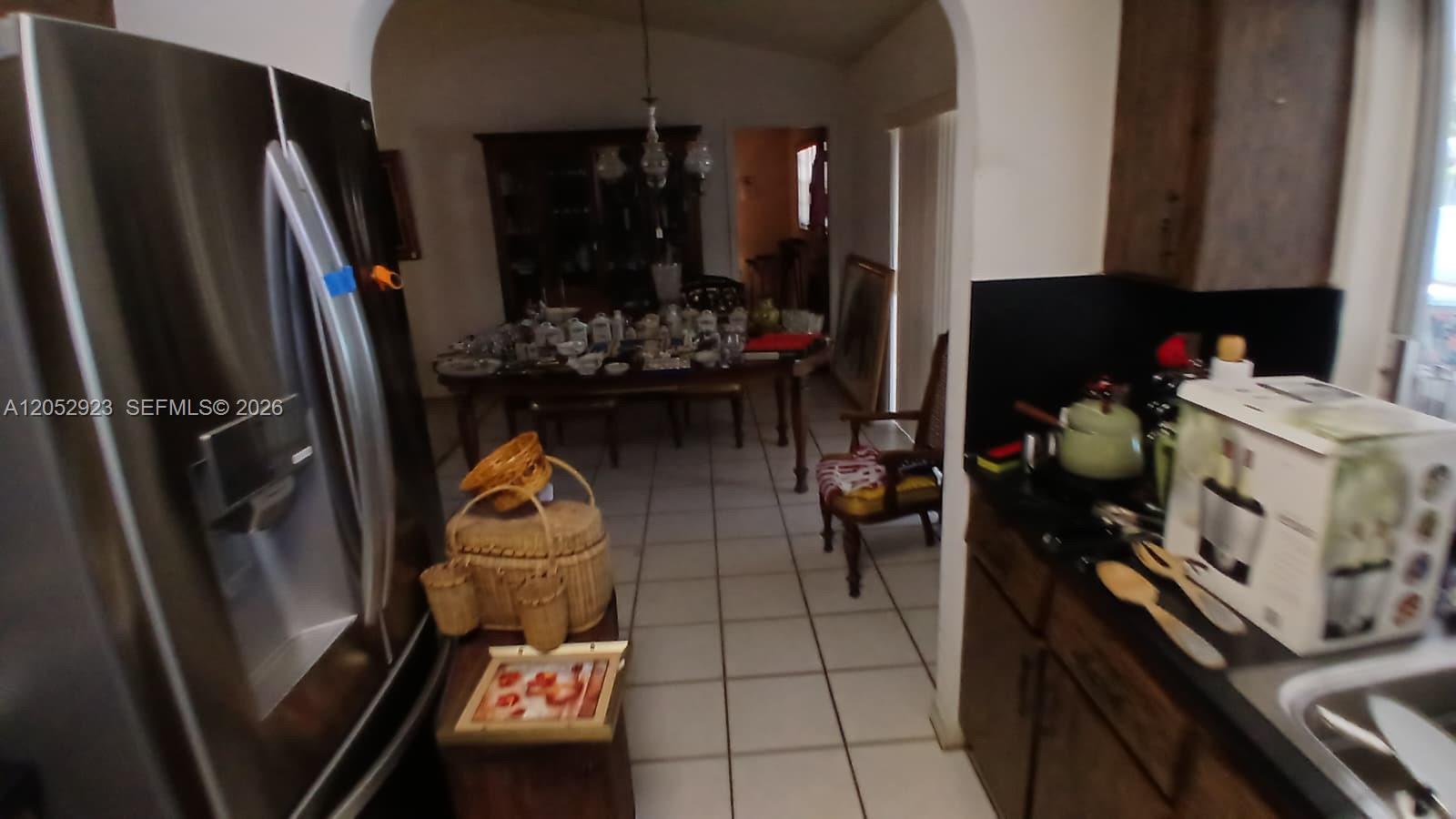 A kitchen with dark cabinets and stainless steel appliances opens into a dining room area — CORAL SPRINGS, FL
