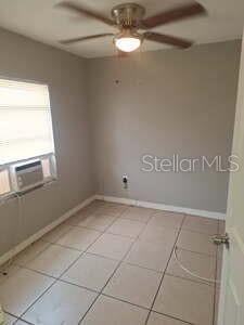 A small bedroom with light-colored tile flooring, a ceiling fan, and a window air conditioner — 1900 BAYSHORE ROAD UNIT C, PALMETTO, FL