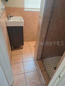 A small bathroom features a pedestal sink, tiled walls, and a walk-in shower — 1900 BAYSHORE ROAD UNIT C, PALMETTO, FL