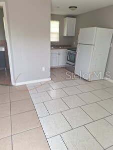 A kitchen with white cabinets, a white refrigerator, and light-colored square floor tiles — 1900 BAYSHORE ROAD UNIT C, PALMETTO, FL