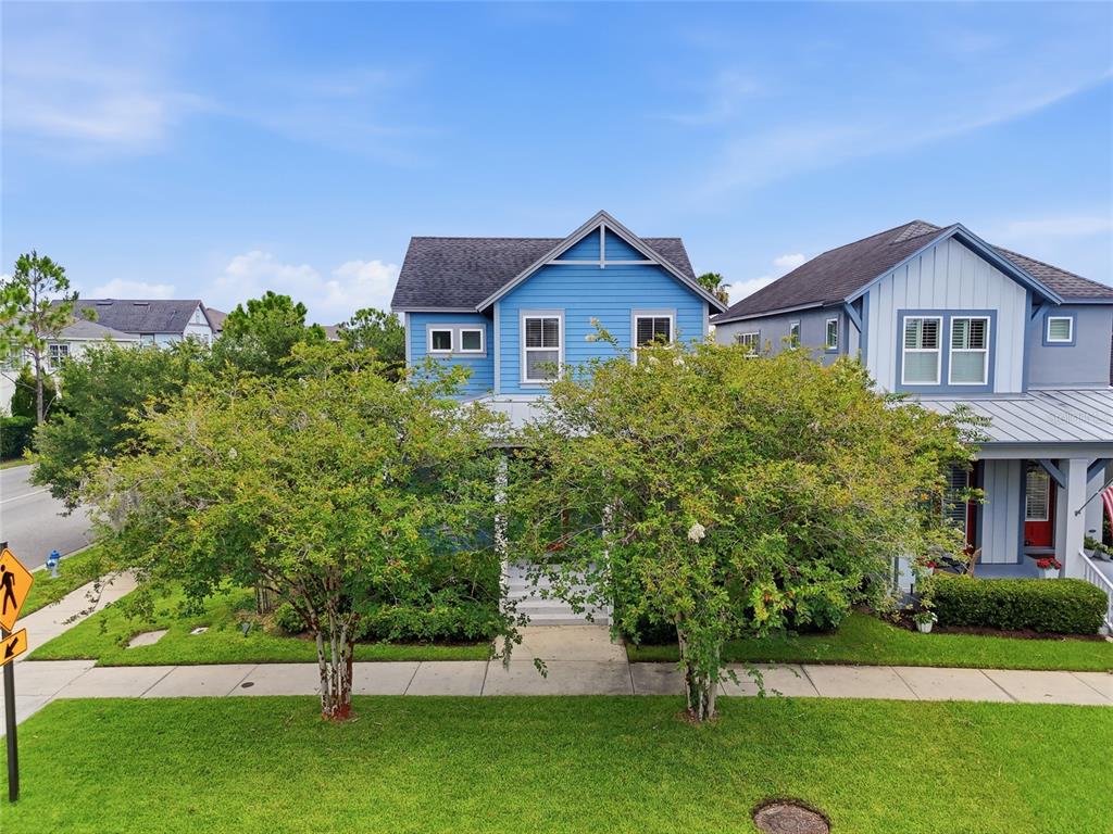 A blue two-story house with a front porch sits behind two large trees — 8105 LAUREATE BOULEVARD, ORLANDO, FL