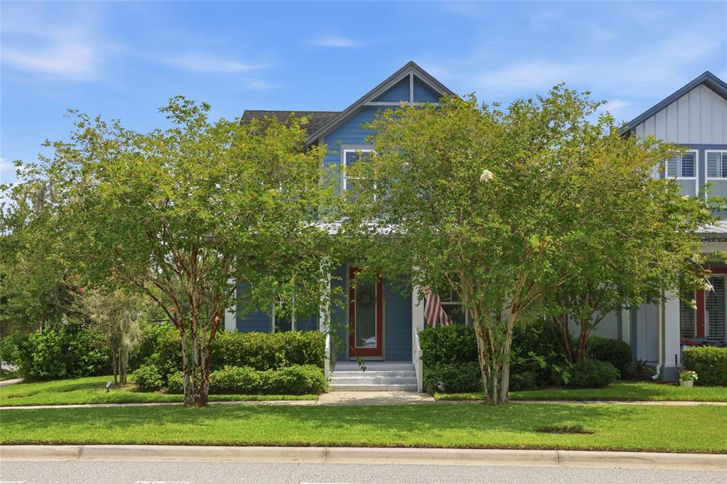 A blue two-story house with a front porch and two large trees in the yard — 8105 LAUREATE BOULEVARD, ORLANDO, FL