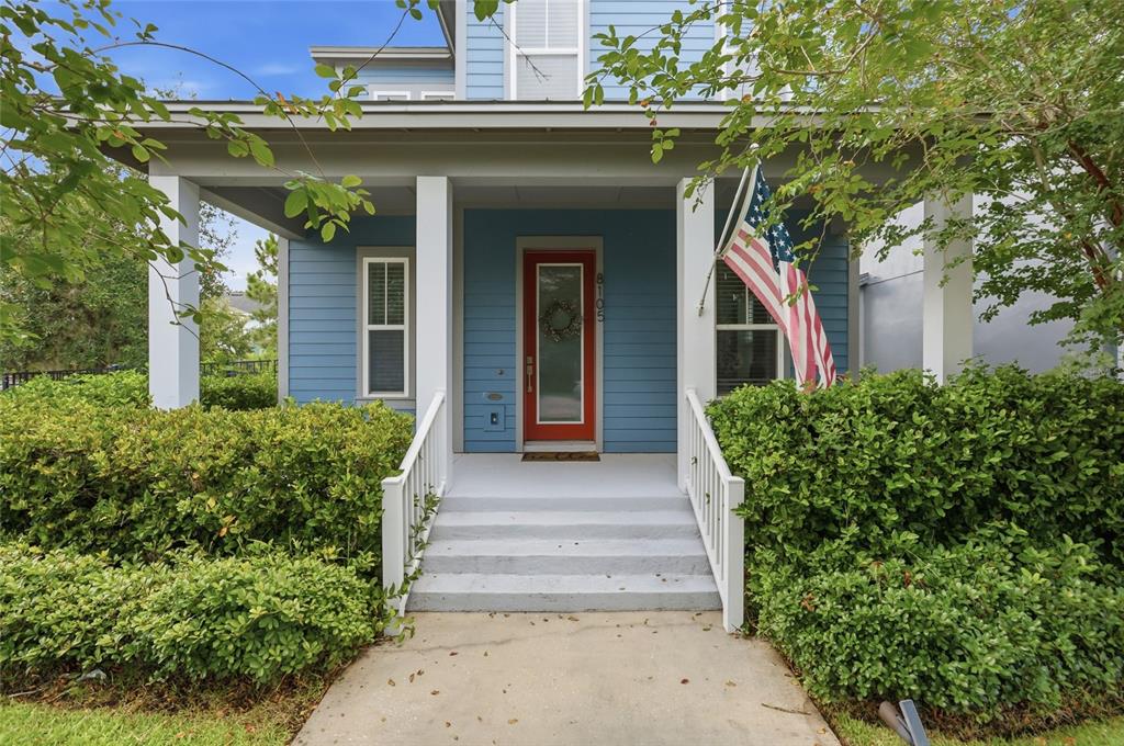 A blue house with a red front door, a front porch, and an American flag — 8105 LAUREATE BOULEVARD, ORLANDO, FL
