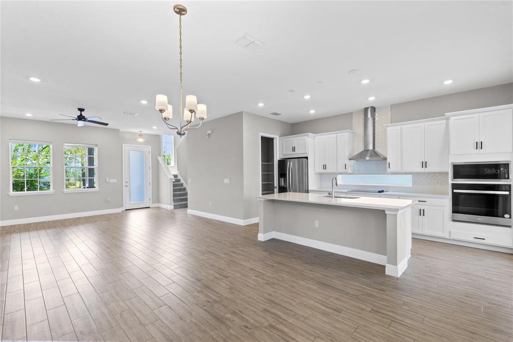 A modern kitchen with white cabinets, a central island, and wood-look tile flooring — 10205 PEARSON AVENUE, ORLANDO, FL