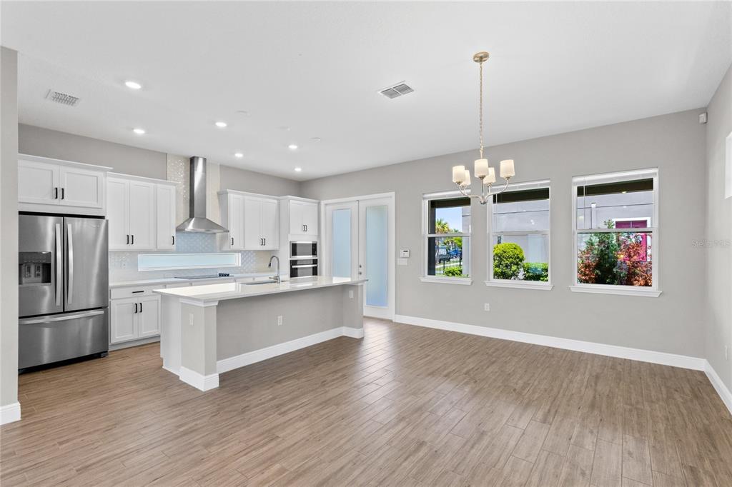 A modern kitchen and dining area with white cabinets, stainless appliances, and wood-look flooring — 10205 PEARSON AVENUE, ORLANDO, FL
