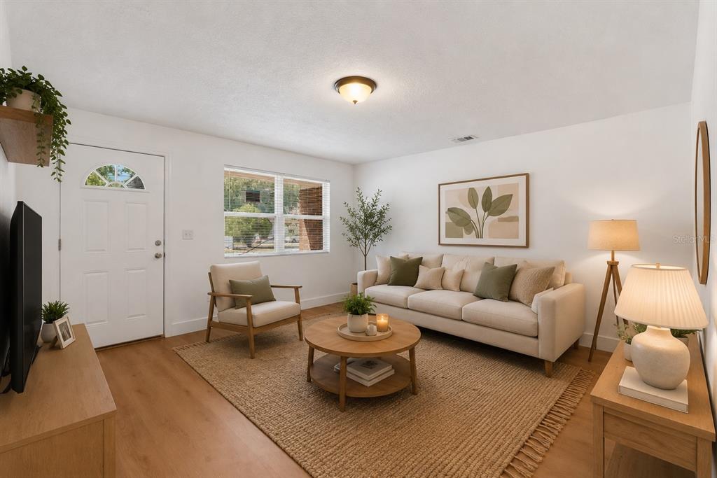 A living room features a beige sofa, round wooden coffee table, and light wood flooring — 5557 CLEVELAND ROAD, JACKSONVILLE, FL