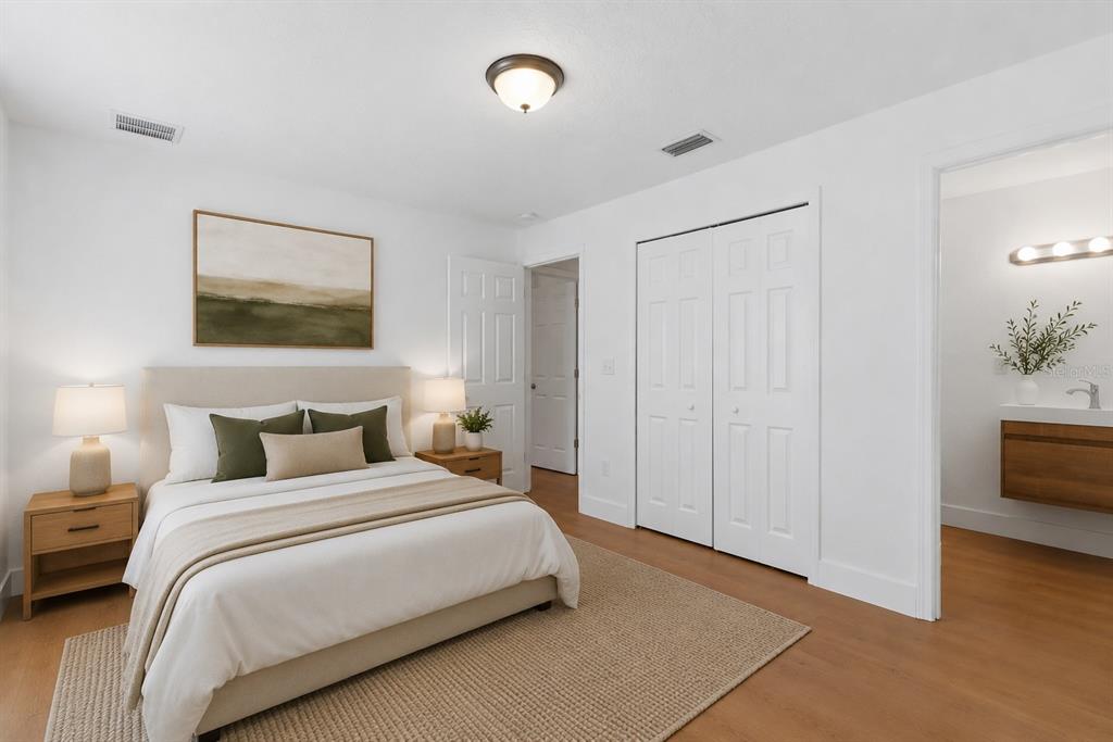 A bedroom with a bed, nightstands, a closet, and an attached bathroom with wood vanity — 5557 CLEVELAND ROAD, JACKSONVILLE, FL