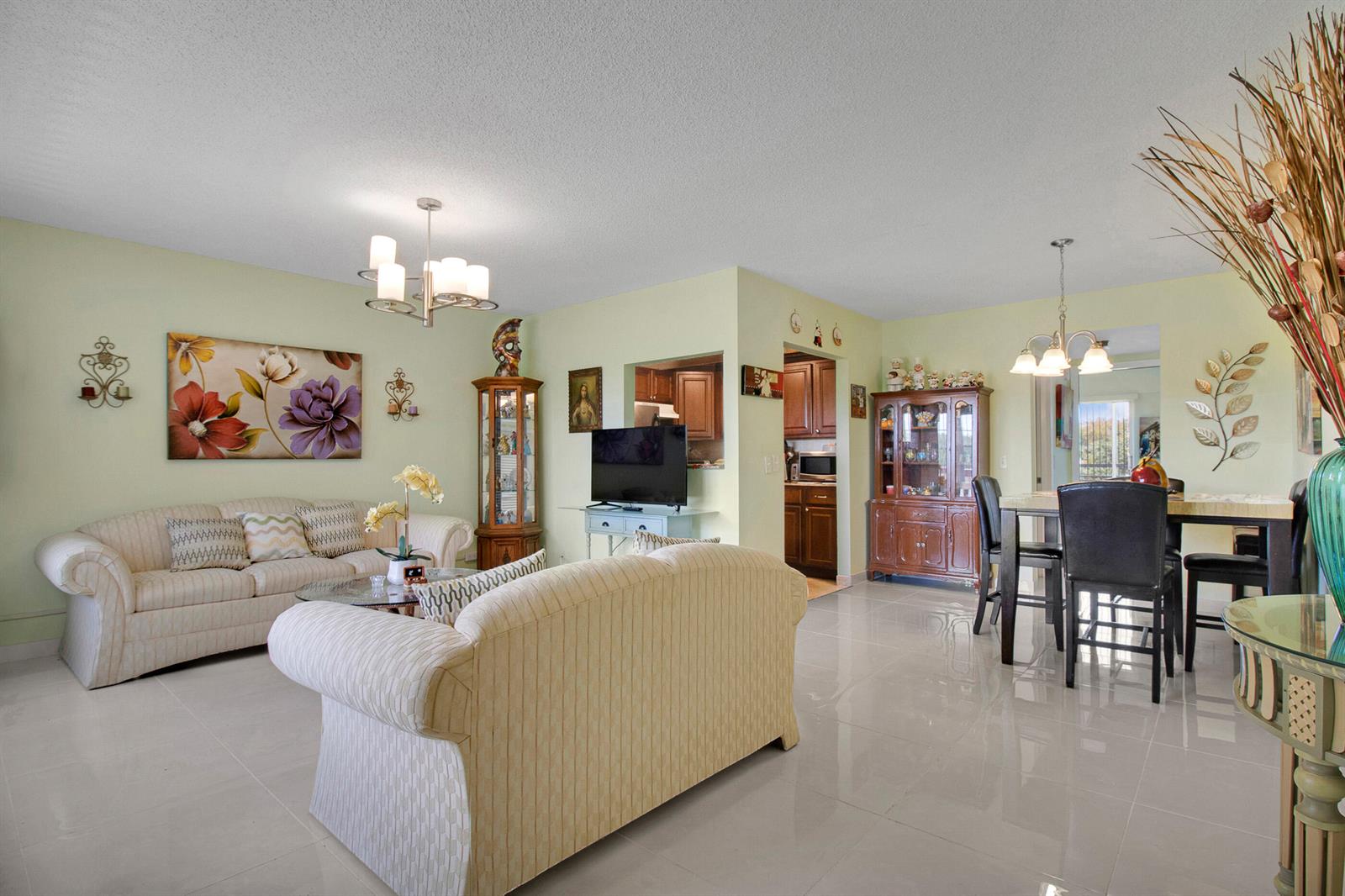A living room and dining area with light green walls, tile floors, and two sofas — 412 Brighton J, Boca Raton FL 33434, BOCA RATON, FL
