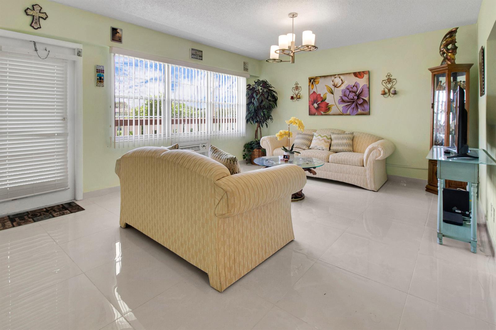 A living room features light-colored tile floors, two beige sofas, and a glass coffee table — 412 Brighton J, Boca Raton FL 33434, BOCA RATON, FL
