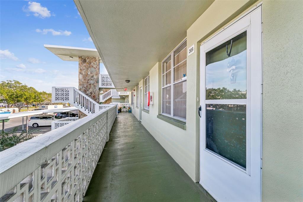 An exterior walkway leads to a white door marked 203 at a multi-story apartment building — 4885 1ST STREET NE UNIT 203, ST PETERSBURG, FL