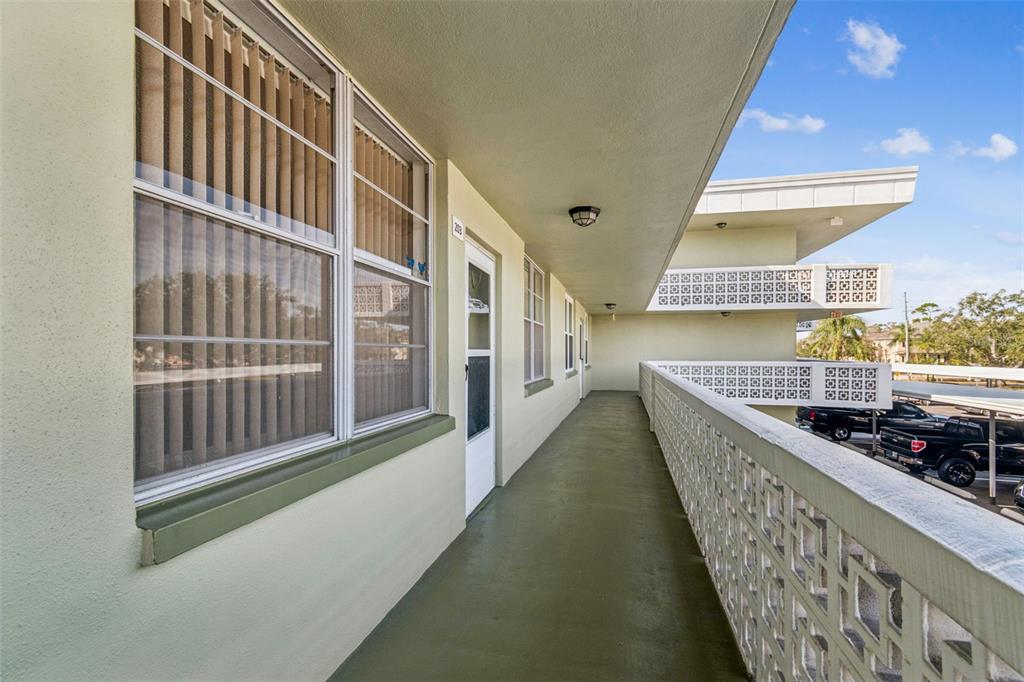 An outdoor walkway with a decorative concrete railing overlooks a parking lot — 4885 1ST STREET NE UNIT 203, ST PETERSBURG, FL