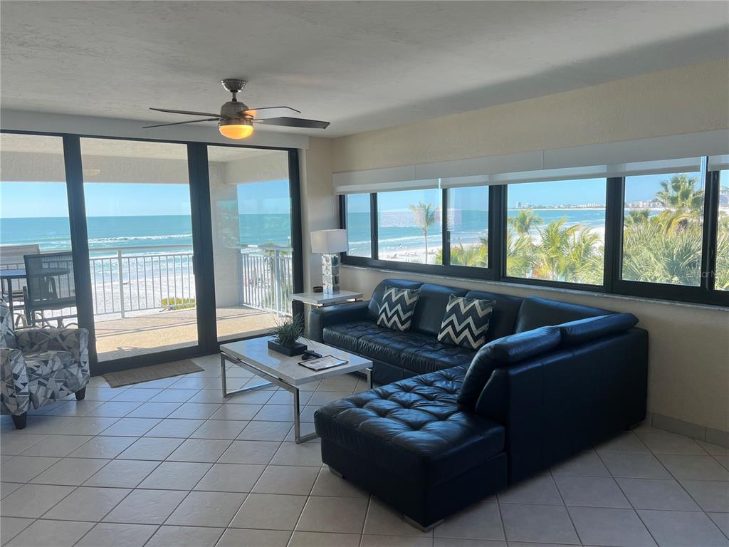 A living room with a black sectional sofa, tile flooring, and floor-to-ceiling ocean views — 1001 POINT OF ROCKS ROAD UNIT 412, SARASOTA, FL