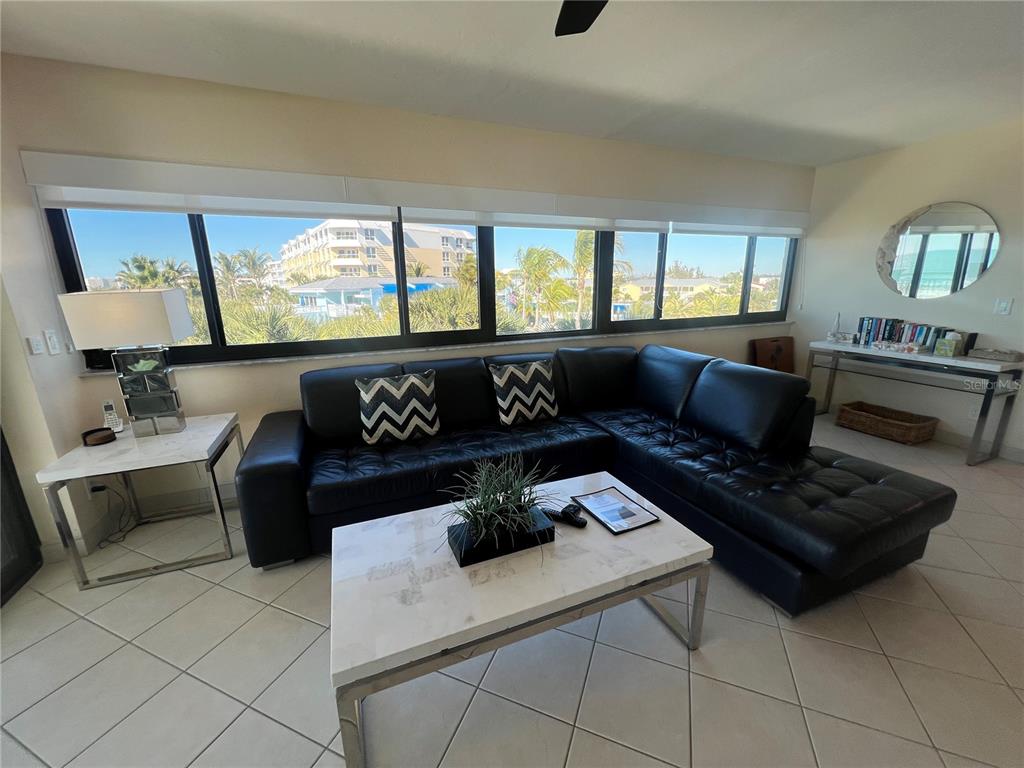 A living room features a black leather sectional, a marble coffee table, and large windows — 1001 POINT OF ROCKS ROAD UNIT 412, SARASOTA, FL