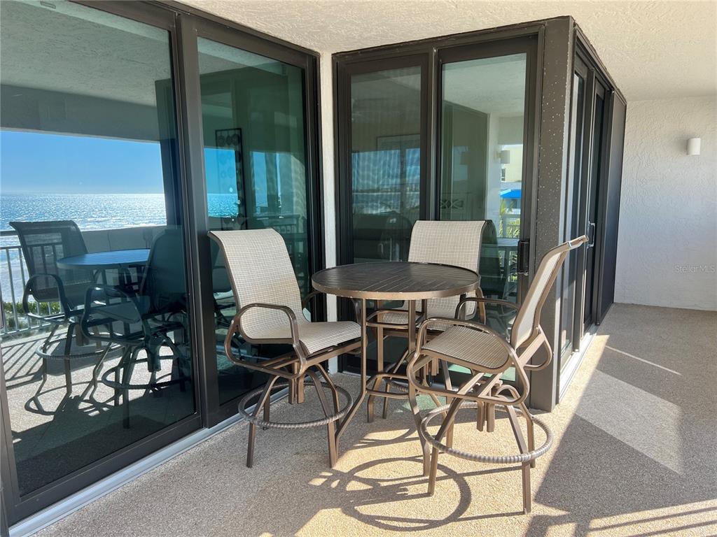 A balcony features a small round table with three chairs overlooking the ocean — 1001 POINT OF ROCKS ROAD UNIT 412, SARASOTA, FL