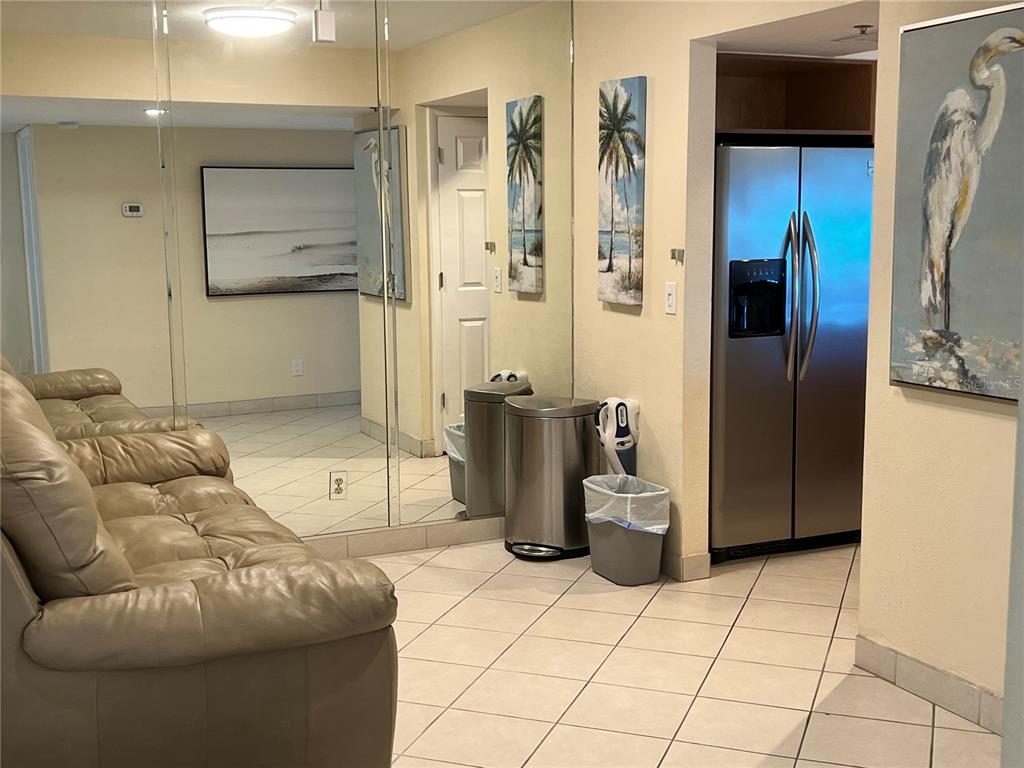 A room with light tile flooring, a leather sofa, mirrored walls, and a stainless refrigerator — 1001 POINT OF ROCKS ROAD UNIT 412, SARASOTA, FL