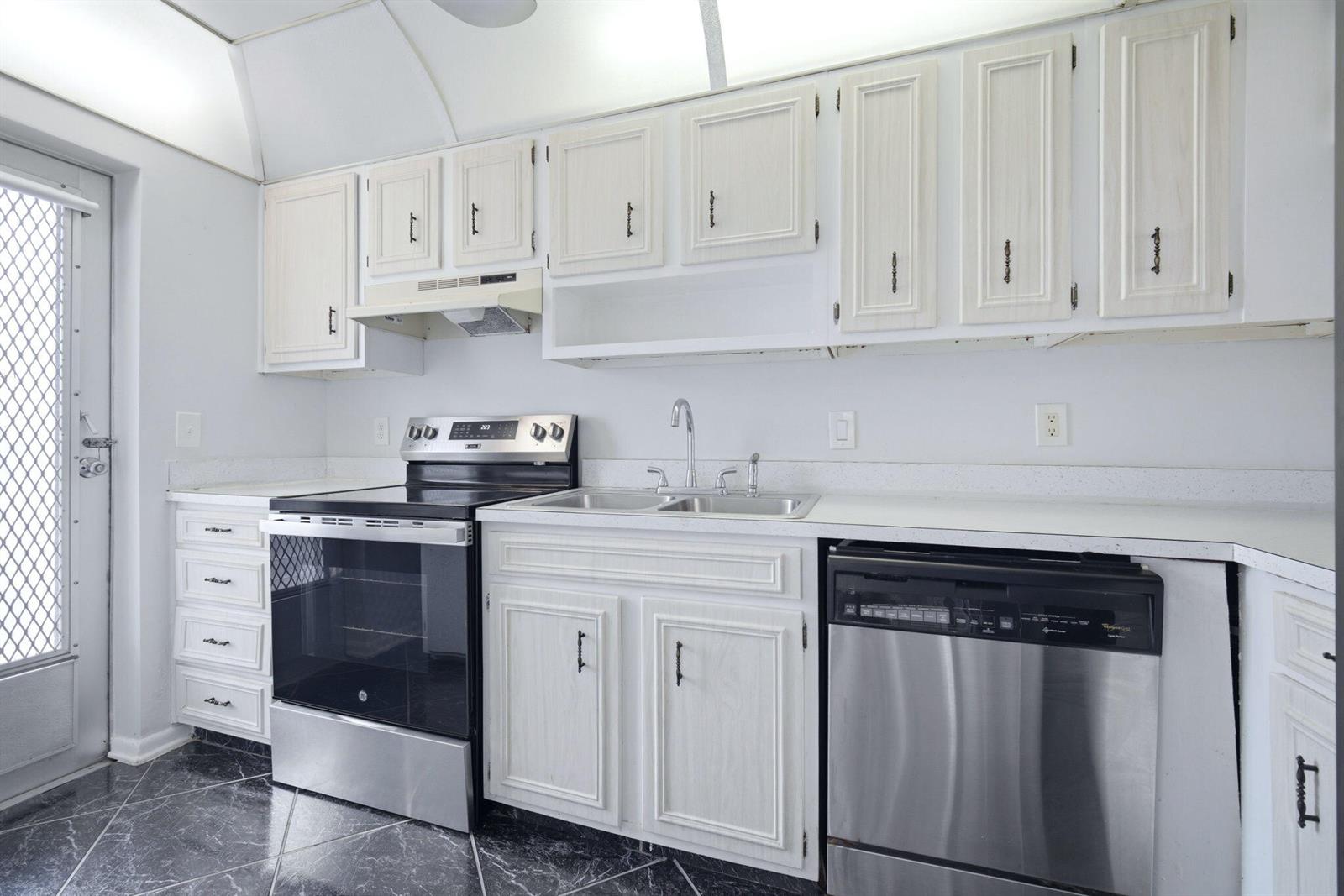 A kitchen features white cabinets, stainless steel appliances, a double sink, and dark tiled flooring — 4502 N Federal Highway # 125C, Lighthouse Point FL 33064, LIGHTHOUSE POINT, FL