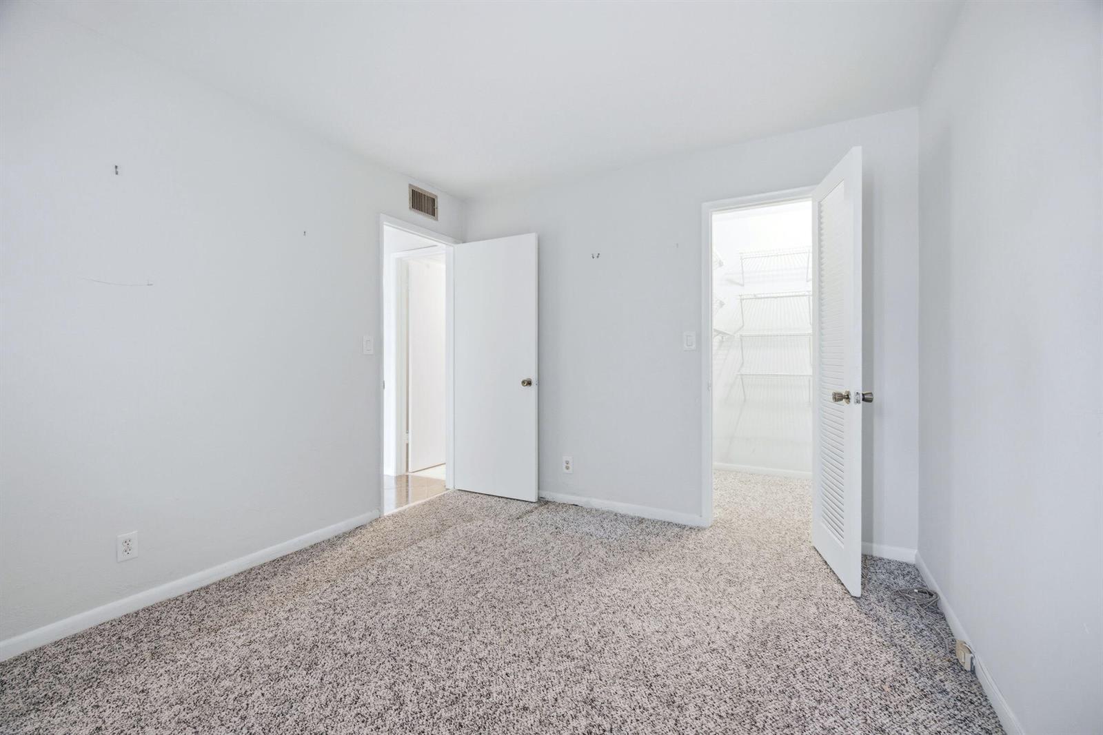 An empty bedroom features gray carpet, white walls, two open doorways, and a walk-in closet — 4502 N Federal Highway # 125C, Lighthouse Point FL 33064, LIGHTHOUSE POINT, FL