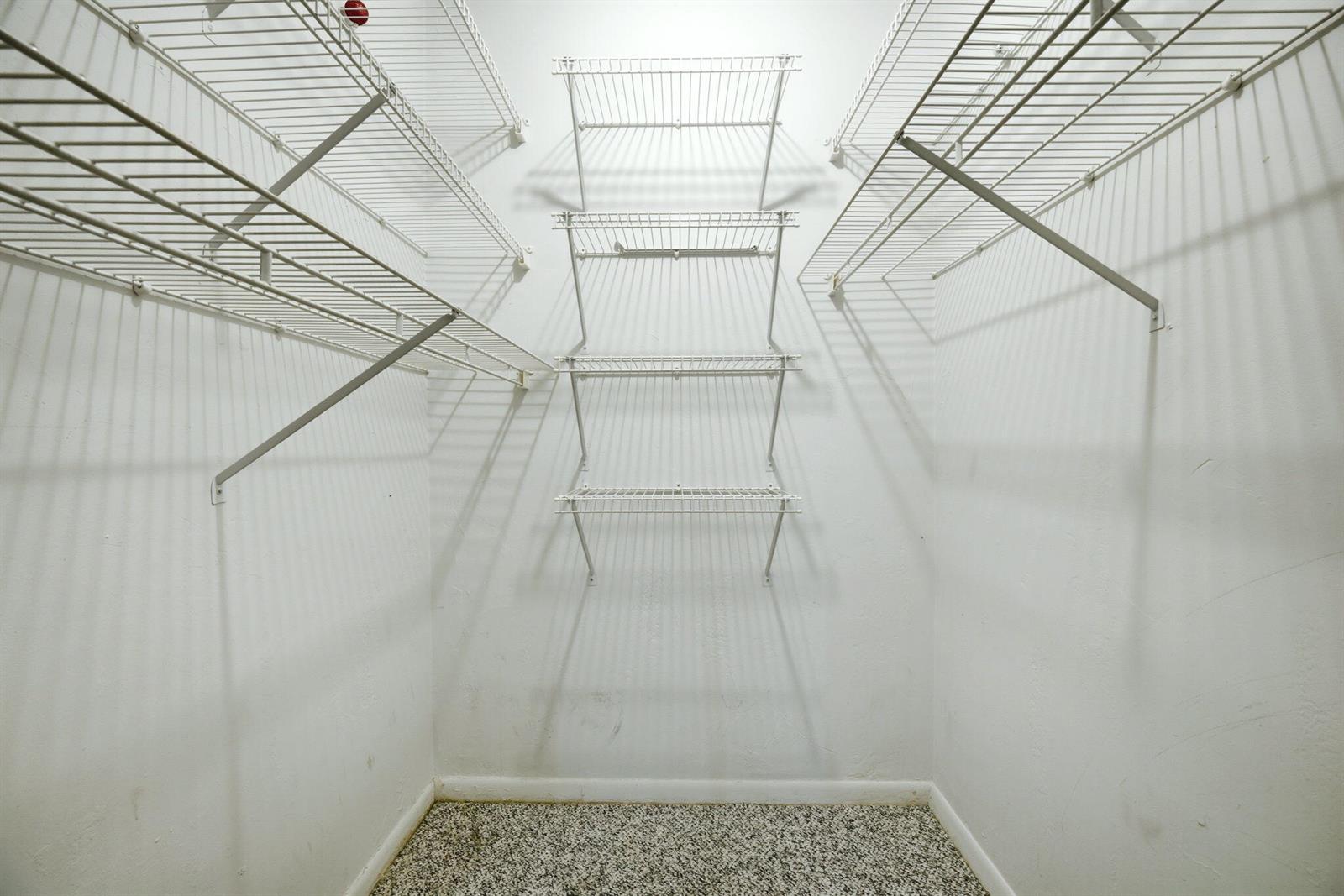A walk-in closet features white wire shelving units mounted on the walls above carpeted flooring — 4502 N Federal Highway # 125C, Lighthouse Point FL 33064, LIGHTHOUSE POINT, FL