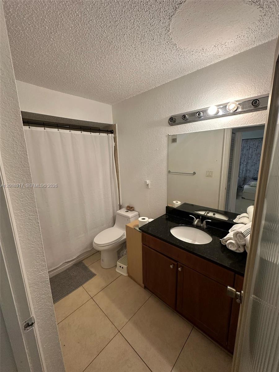 This bathroom features a black granite vanity, a white toilet, and a shower-tub combination — 15640 SW 106th Ln # 903, Miami FL 33196, MIAMI, FL