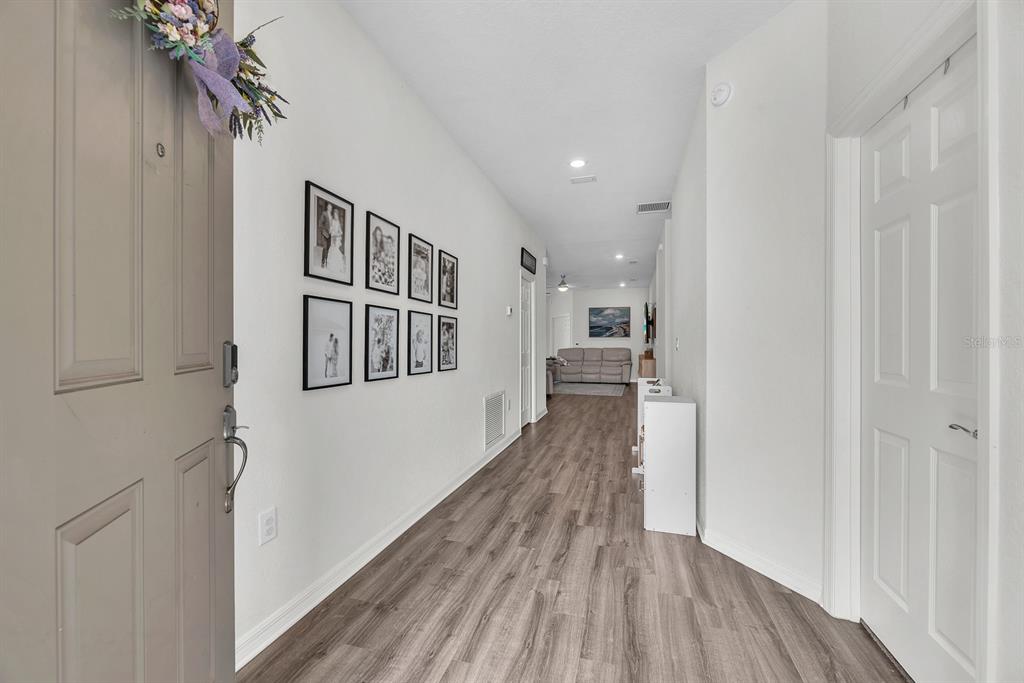 A hallway with wood-look flooring leads from an entryway toward a living area — 6543 166TH PLACE E, PARRISH, FL