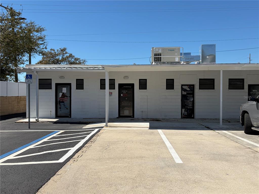 A single-story white commercial building with a parking lot sits under a clear blue sky — 3418 W SWANN AVENUE UNIT 200, TAMPA, FL