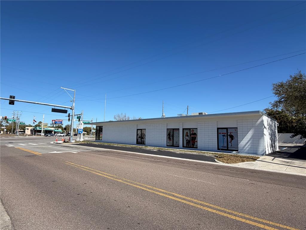 A single-story white commercial building with three glass-paneled doors and a paved parking lot — 3418 W SWANN AVENUE UNIT 200, TAMPA, FL