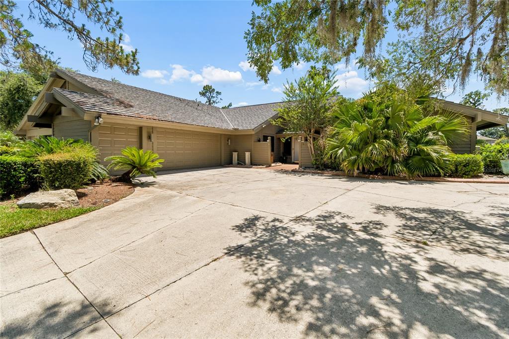 A single-story house with a large concrete driveway, two-car garage, and lush landscaping — 5335 SAND CRANE COURT, WESLEY CHAPEL, FL