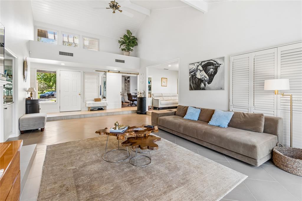 A spacious living room features a vaulted ceiling, tile flooring, and a large brown sofa — 5335 SAND CRANE COURT, WESLEY CHAPEL, FL