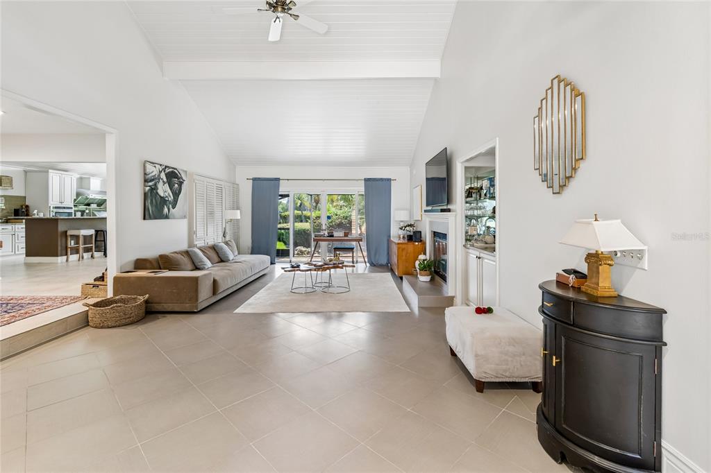 A spacious living room features vaulted ceilings, tile flooring, a fireplace, and sliding glass doors — 5335 SAND CRANE COURT, WESLEY CHAPEL, FL