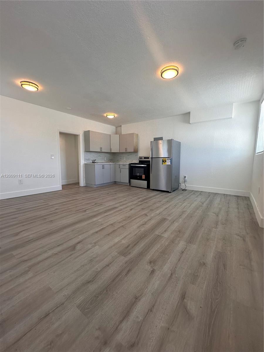 This open-concept kitchen features light-colored cabinets, stainless steel appliances, and wood-look flooring — 50 NW 79th St # 6, Miami FL 33150, MIAMI, FL