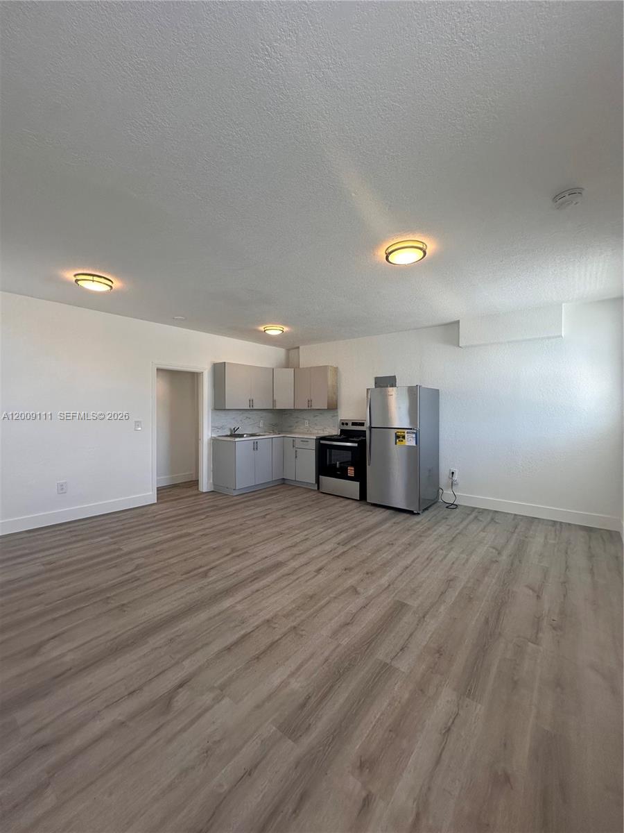 A kitchen with light gray cabinets and stainless steel appliances sits in an open room — 50 NW 79th St # 6, Miami FL 33150, MIAMI, FL