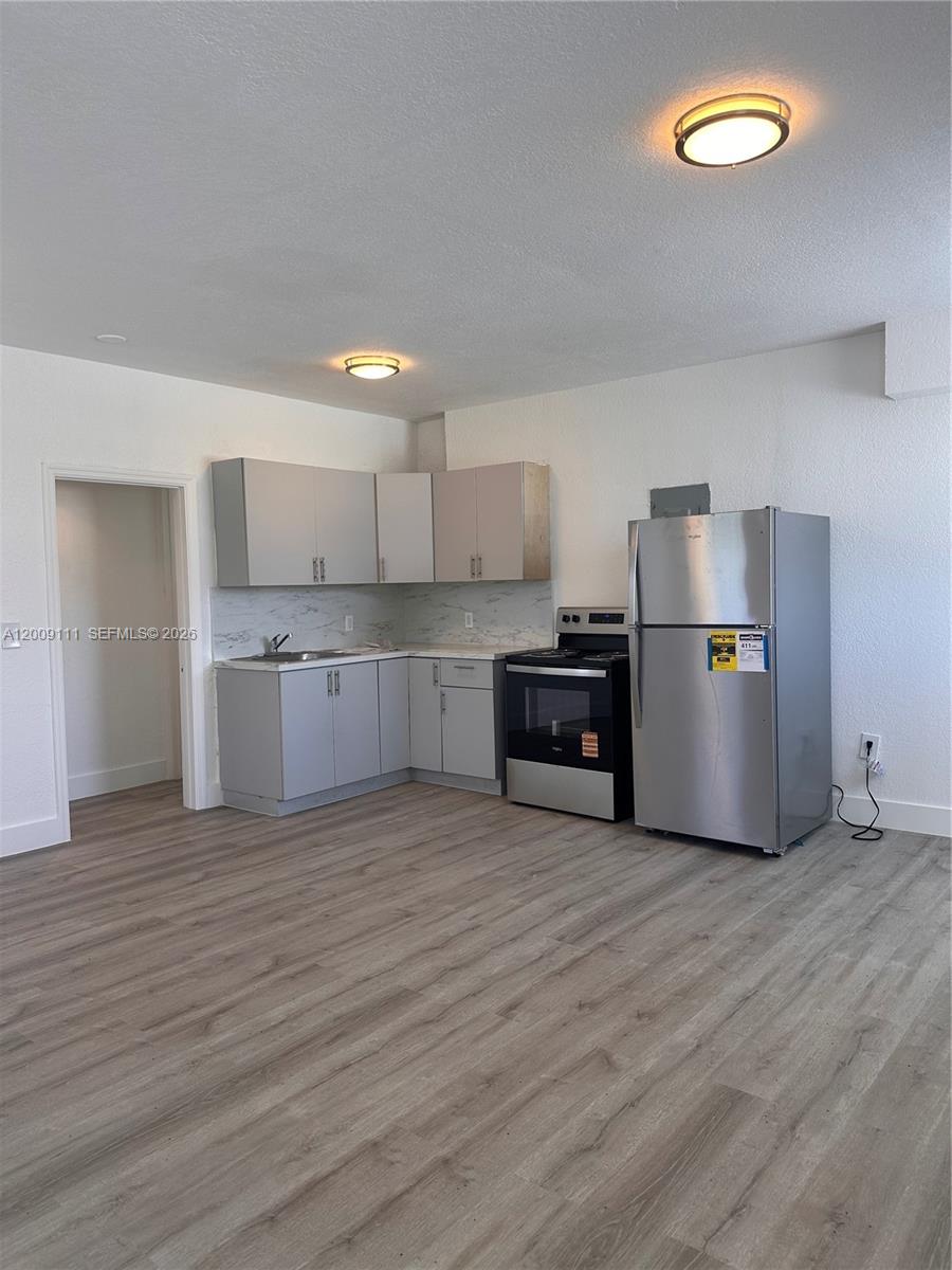 A kitchen features light gray cabinets, stainless steel appliances, and wood-look flooring — 50 NW 79th St # 6, Miami FL 33150, MIAMI, FL