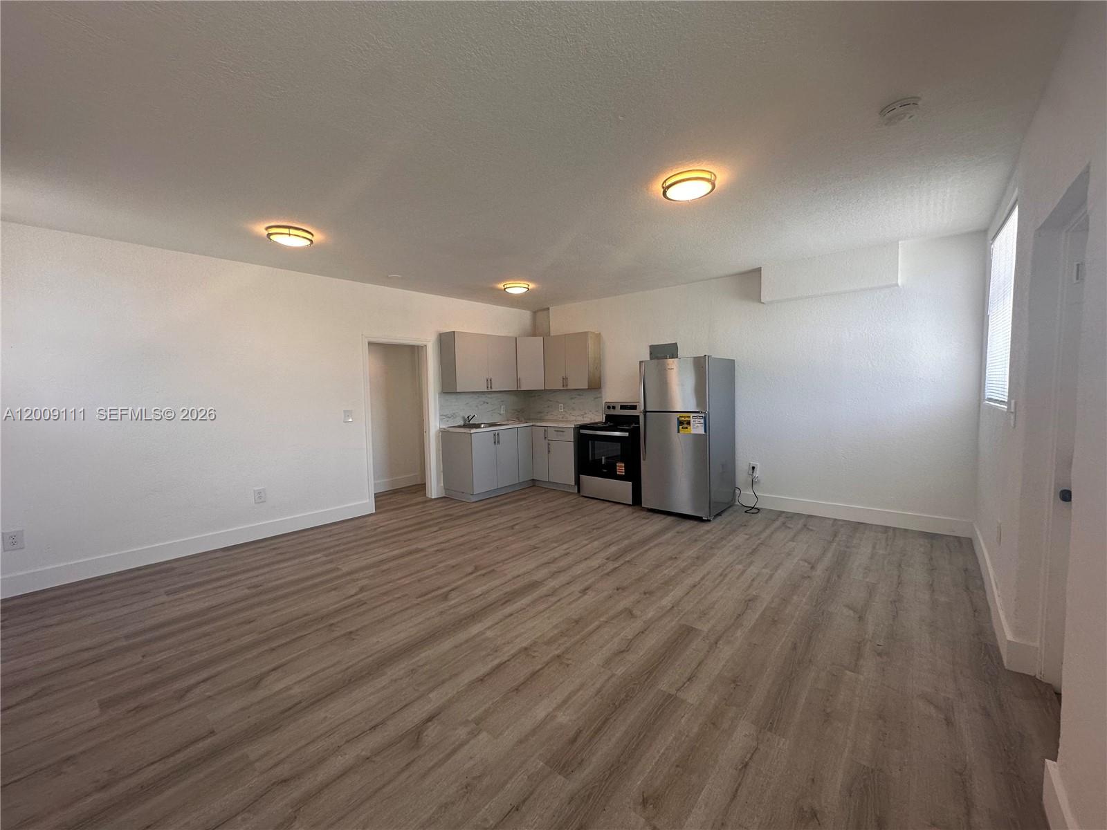 A kitchen area features light-colored cabinets, stainless steel appliances, and wood-look flooring — 50 NW 79th St # 6, Miami FL 33150, MIAMI, FL