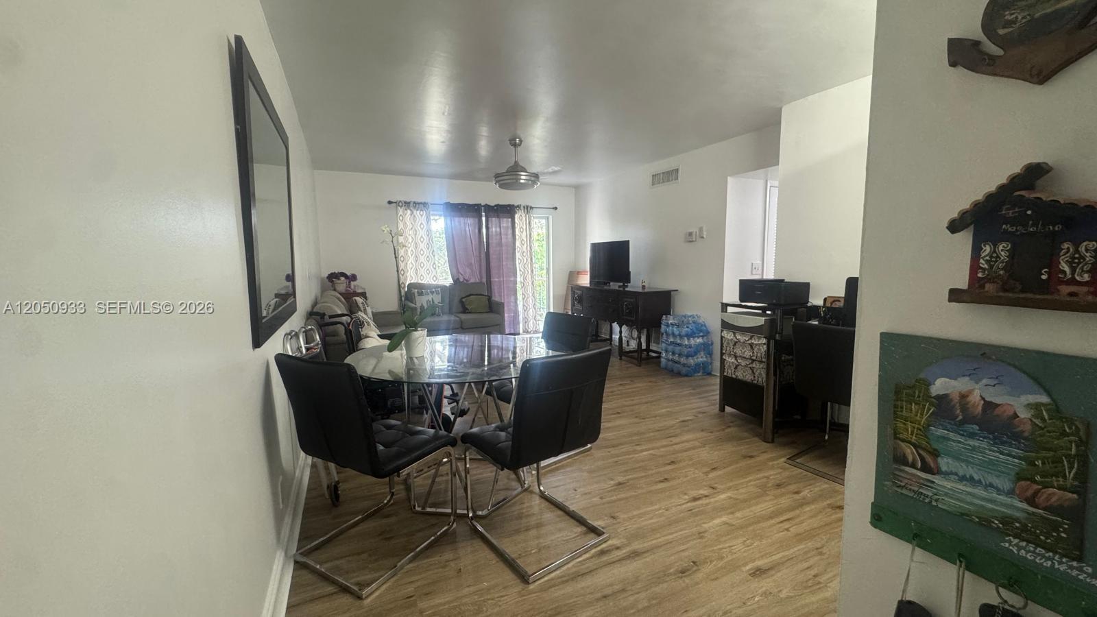 A dining area with a glass table and black chairs opens into a living room — 636 NW 13th St # 0230, Boca Raton FL 33486, BOCA RATON, FL