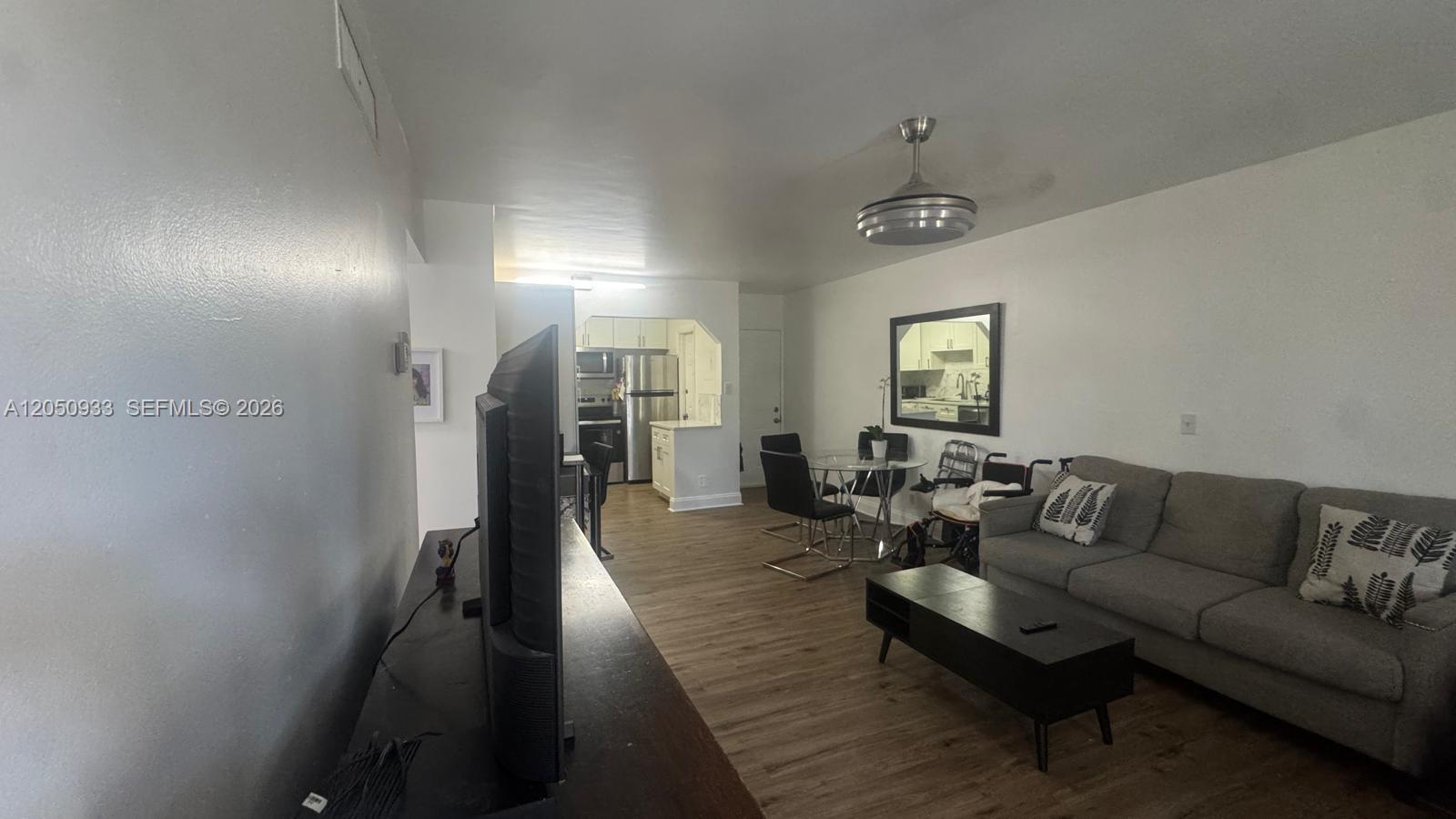 This living room features wood-look flooring, a gray sofa, a coffee table, and a kitchen — 636 NW 13th St # 0230, Boca Raton FL 33486, BOCA RATON, FL