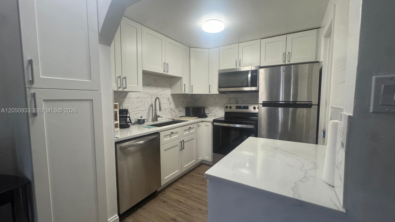A kitchen features white cabinets, stainless steel appliances, and white marble-patterned countertops — 636 NW 13th St # 0230, Boca Raton FL 33486, BOCA RATON, FL
