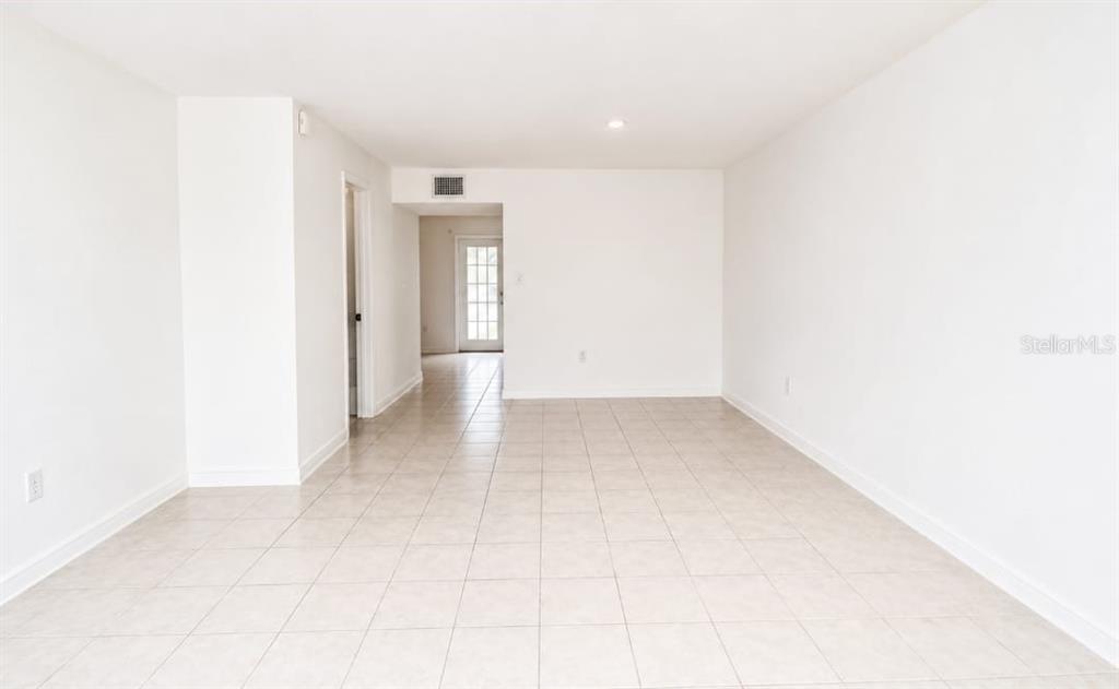 An empty room with white walls, tile flooring, and a doorway leading to an exterior door — 5850 CYPRESS GARDENS BOULEVARD UNIT 608, WINTER HAVEN, FL