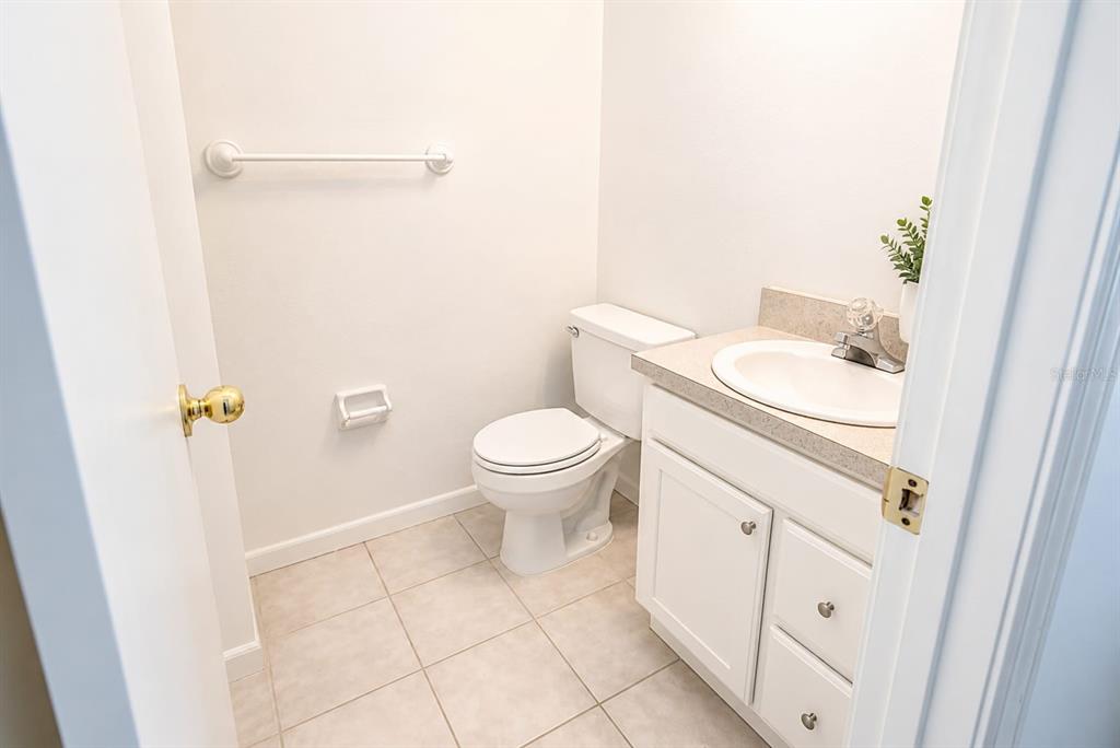 A small bathroom features a white toilet, a vanity with a sink, and tiled flooring — 5850 CYPRESS GARDENS BOULEVARD UNIT 608, WINTER HAVEN, FL