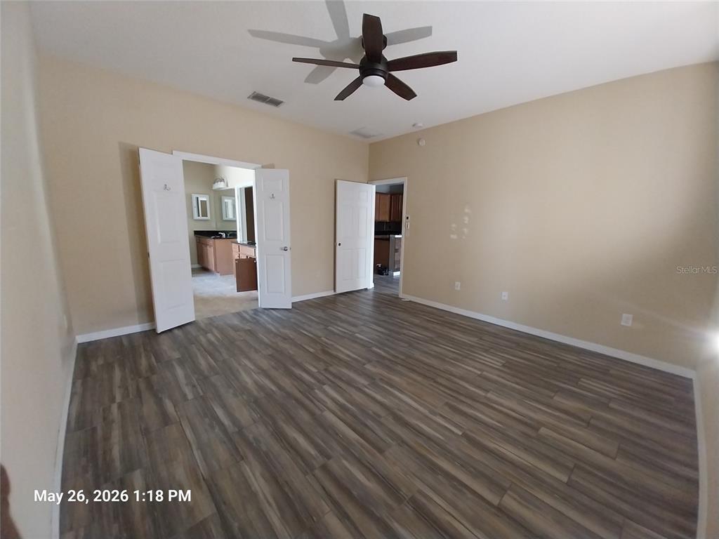 A bedroom with wood-look flooring, a ceiling fan, and open doorways leading to other rooms — 2228 PARROT FISH DRIVE, HOLIDAY, FL