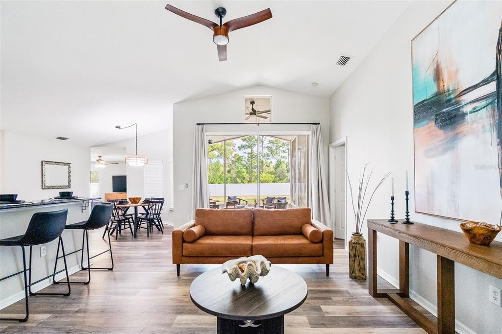A living room with a brown sofa, round coffee table, and view of a patio — 11225 FLOWER AVENUE, WEEKI WACHEE, FL