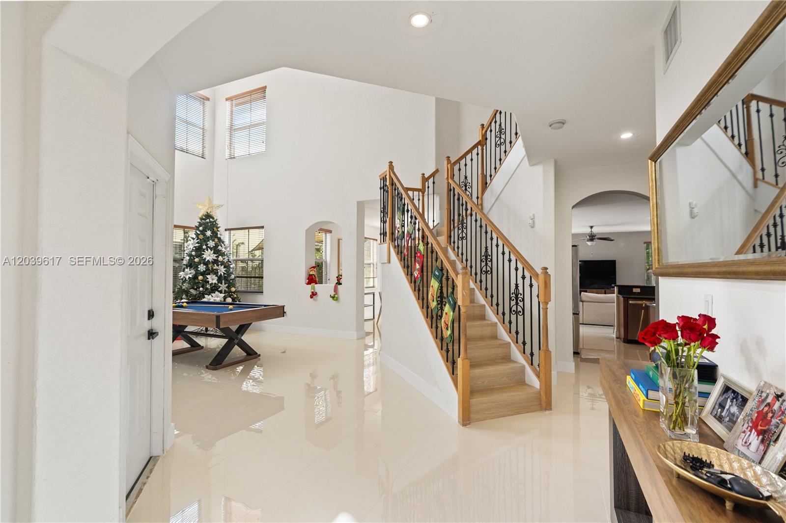 A bright foyer features a staircase with iron railings, a pool table, and tile flooring — 11558 NW 84th  St, Doral FL 33178, DORAL, FL