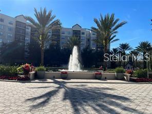 A large fountain sits in front of a multi-story apartment building with palm trees — 14501 GROVE RESORT AVE UNIT 1535, WINTER GARDEN, FL