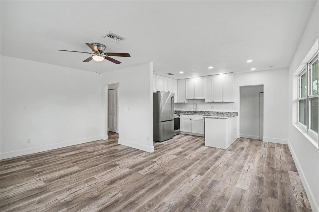 A kitchen with white cabinets and stainless steel appliances opens into a living area — 1423 18TH STREET W, BRADENTON, FL