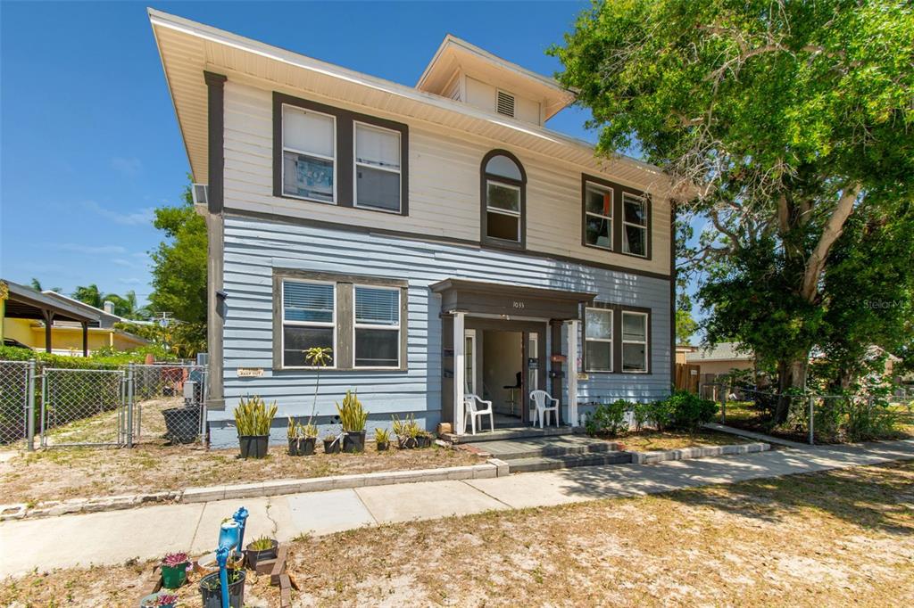 A two-story house with light blue and cream siding features a front porch entrance — 1033 19TH AVENUE S, ST PETERSBURG, FL